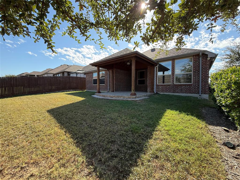 Brick exterior, covered rear patio with wood-column supports, and fenced backyard featuring a natural grass lawn Brick exterior, covered rear patio with wood-column supports, and fenced backyard featuring a natural grass lawn