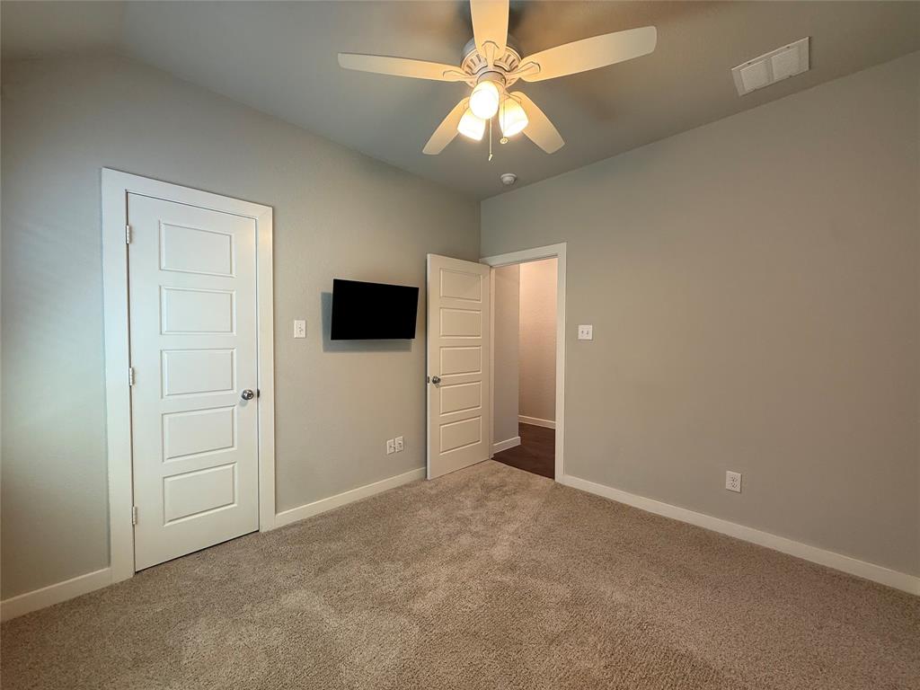 Neutral-toned interior featuring wall-to-wall carpeting, five-panel interior doors, and a ceiling-mounted light fixture with a fan