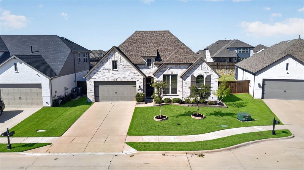 Stone and masonry exterior featuring a multi-gabled roofline, an attached two-car garage, and manicured landscaping