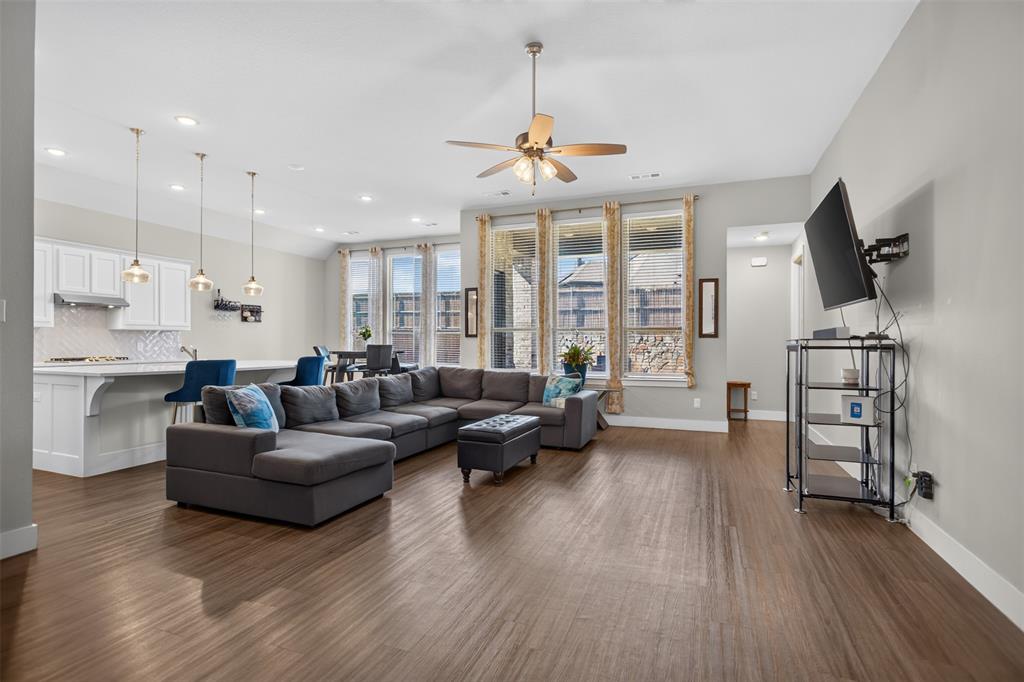 Open concept interior featuring wood-finish flooring, recessed lighting, white cabinetry, a center island with pendant fixtures, and tall windows