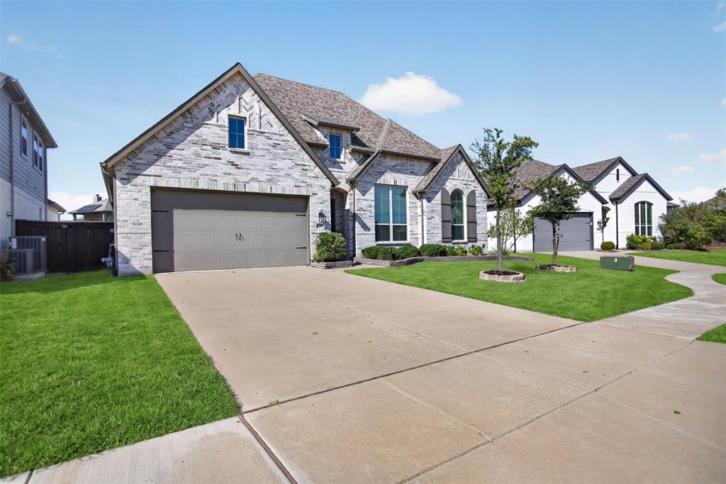 Stone and brick veneer exterior with a concrete driveway, multi-gabled roofline, and arched window detailing