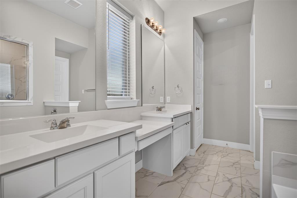 Dual vanity with light-toned cabinetry, solid surface countertops, integrated sinks, chrome fixtures, and large plate-glass mirrors