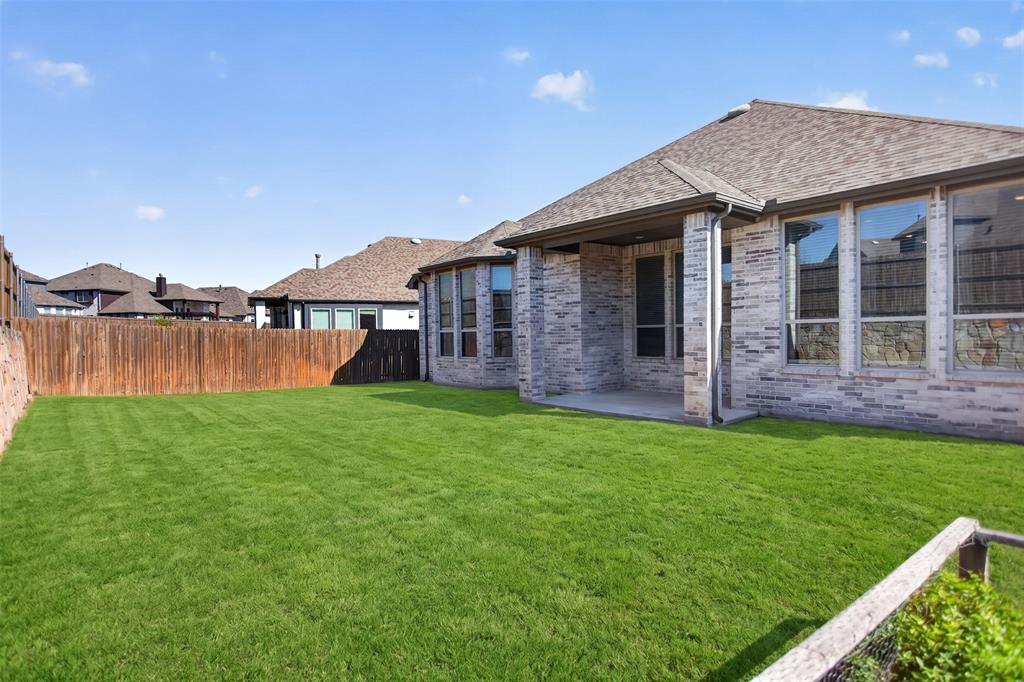Brick exterior siding, covered concrete patio, and fenced backyard with a grass lawn
