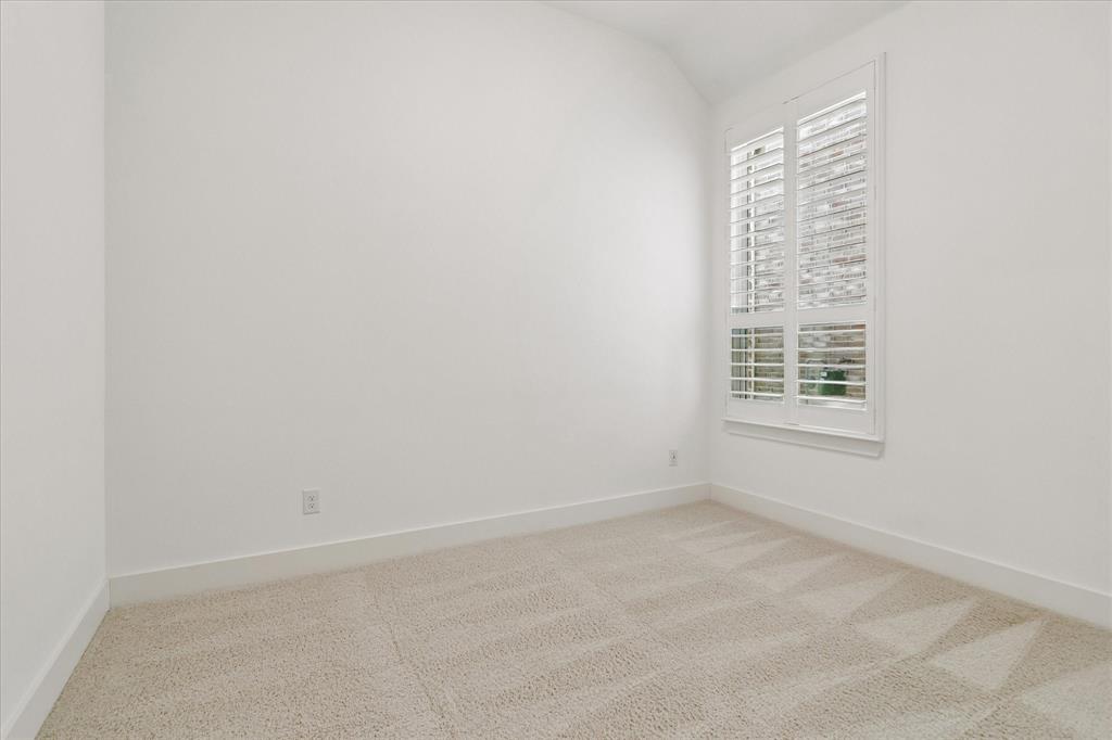 Room featuring neutral carpeting, vaulted ceiling, and white plantation shutters