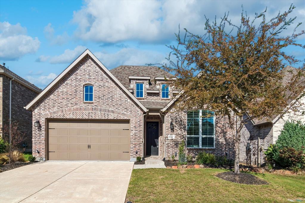 Brick exterior with arched detailing, multi-gabled roofline, concrete driveway, two-car garage, and arched window features Brick exterior with arched detailing, multi-gabled roofline, concrete driveway, two-car garage, and arched window features