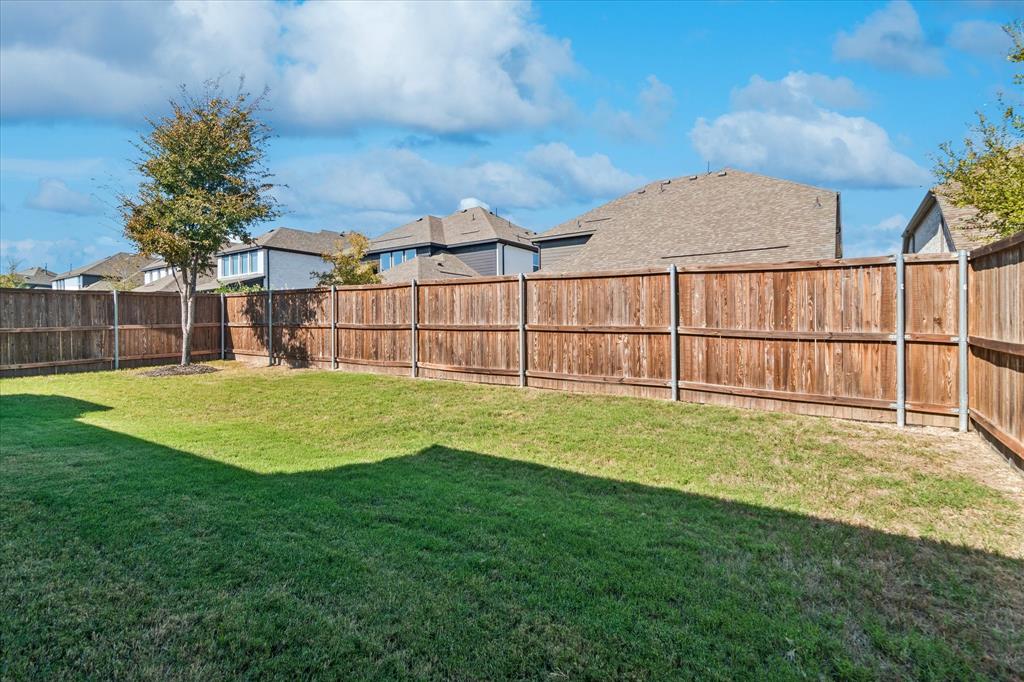 Backyard featuring a grass lawn, wood privacy fencing, and a mature tree