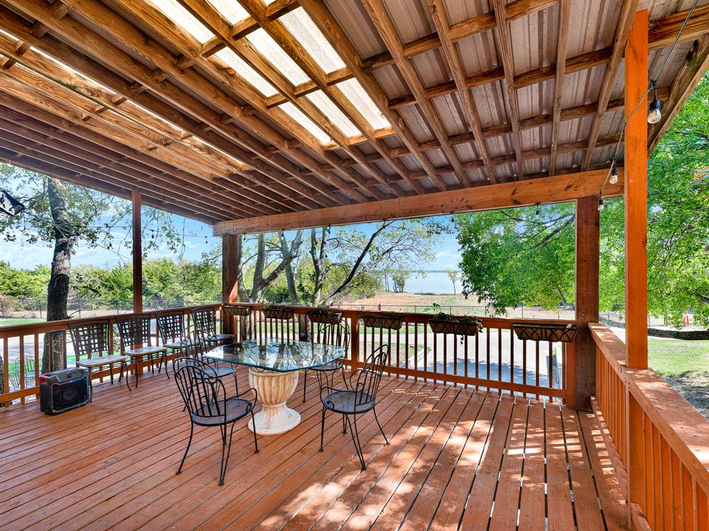 Covered wooden deck featuring a pergola-style roof, built-in wooden railings, and string lighting
