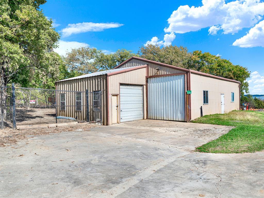 Detached metal structure featuring a corrugated exterior, roll-up overhead door, two pedestrian doors, and a concrete approach