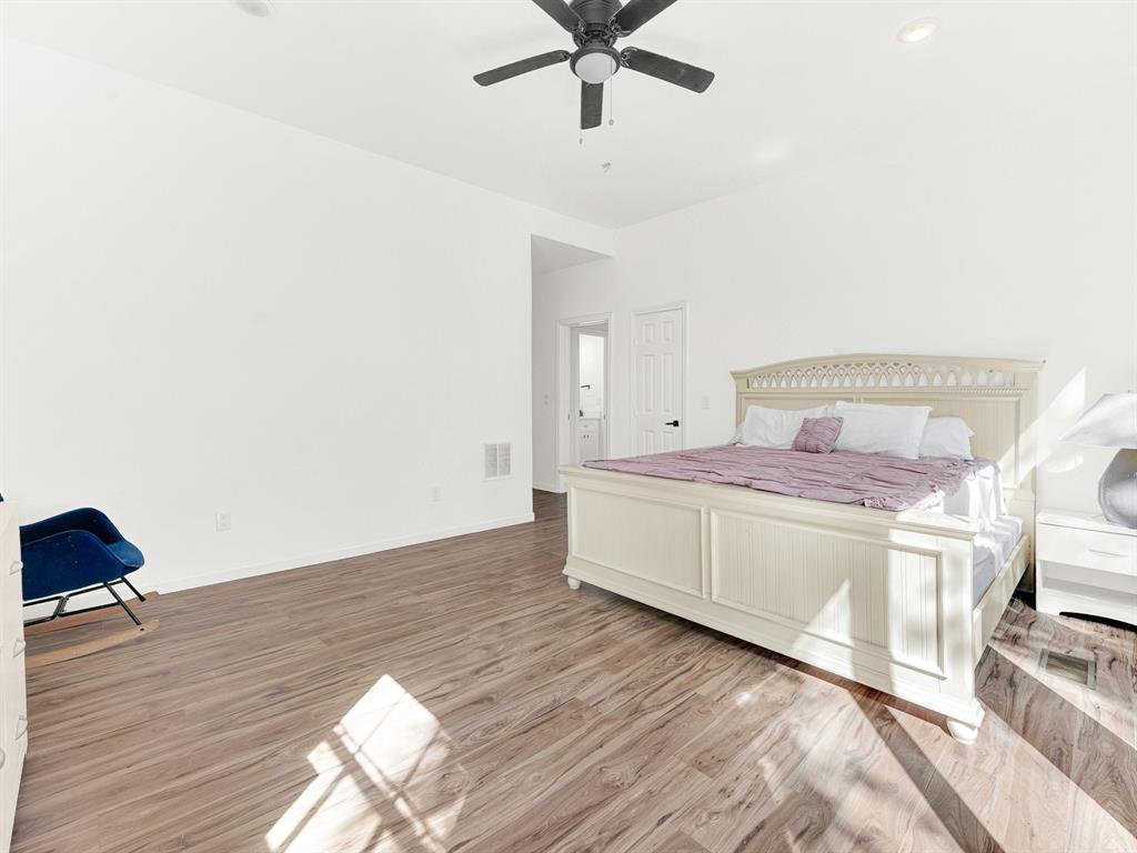 Spacious room featuring wood-finish flooring, high ceilings, recessed lighting, and a ceiling fan
