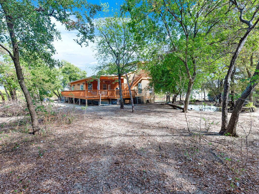 Wood-sided exterior featuring an elevated wraparound deck, exterior staircase, and mature trees on a wooded lot