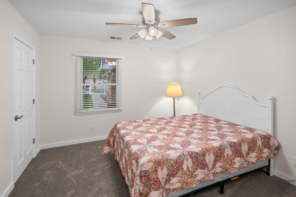 Neutral wall tones, wall-to-wall carpeting, white paneled interior door, and a ceiling-mounted light fixture with a fan
