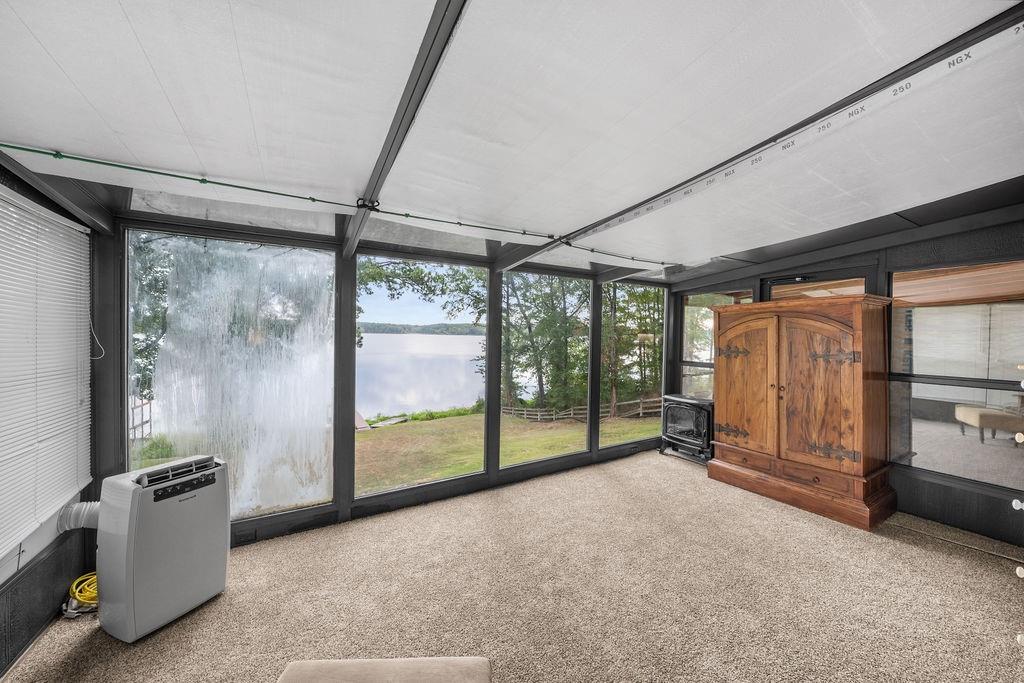 Enclosed sunroom featuring expansive floor-to-ceiling windows, high-contrast dark structural framing, and a carpeted floor