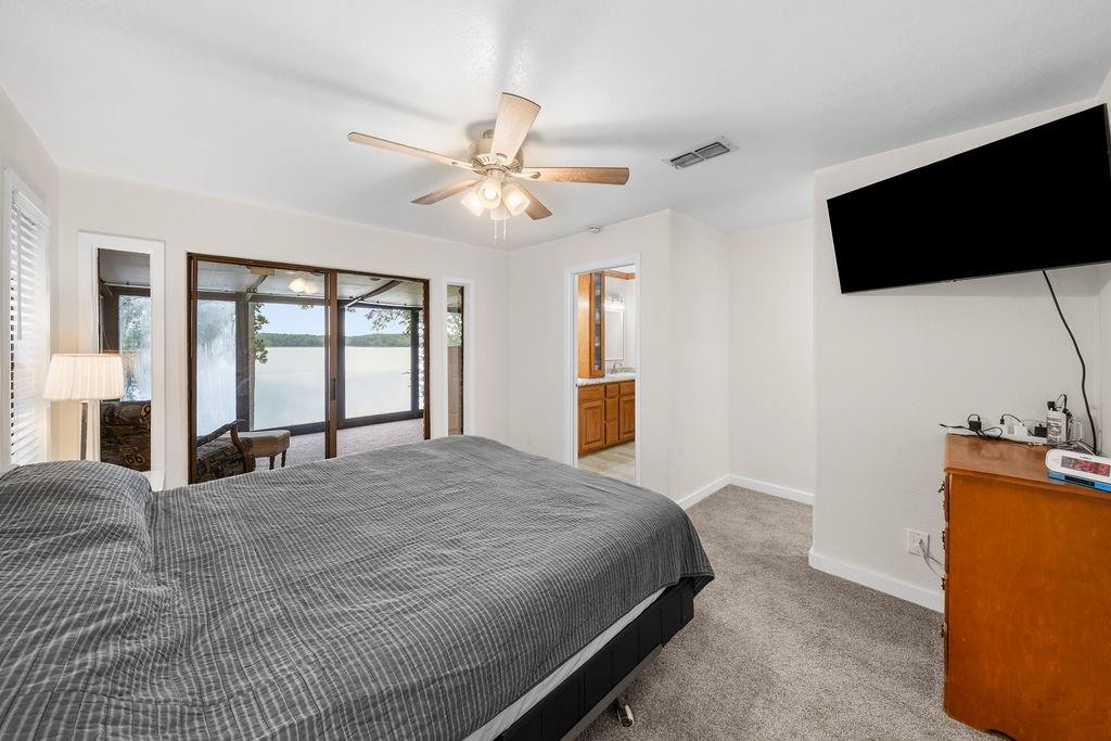 Interior space featuring neutral wall tones, carpeted flooring, a ceiling fan with integrated lighting, and glass sliding doors