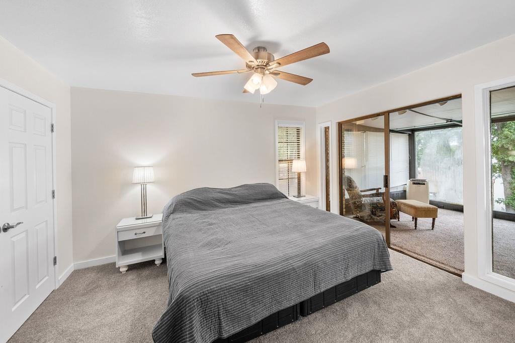 Neutral interior featuring a ceiling fan with integrated lighting, wall-to-wall carpeting, a six-panel door, and sliding glass doors