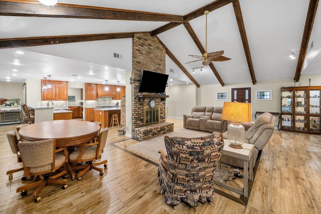 Vaulted ceiling with exposed wood beams, full-height masonry fireplace, and wood-finish flooring