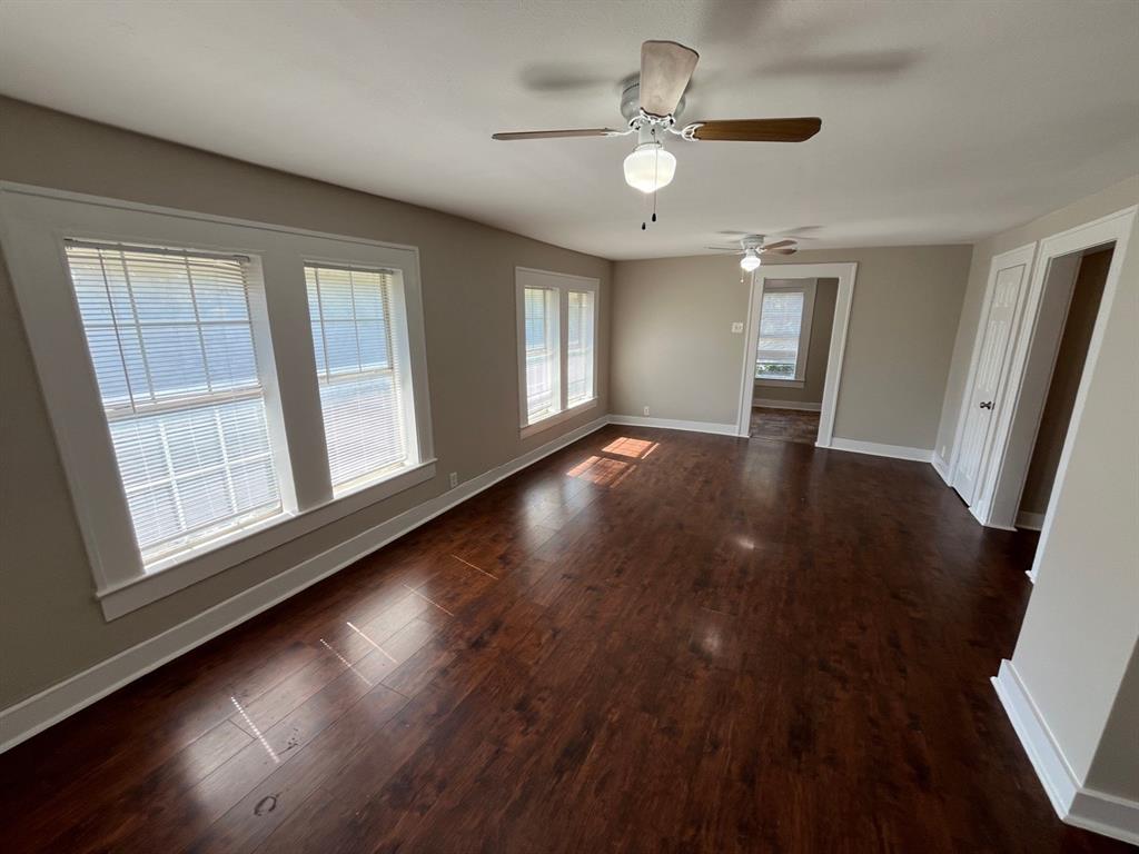 Interior space featuring dark wood-finish flooring, multi-pane windows with trim, and two ceiling fans