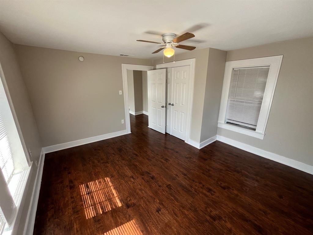 Wood-finish flooring, double-panel closet doors, and a ceiling fan with integrated light fixture