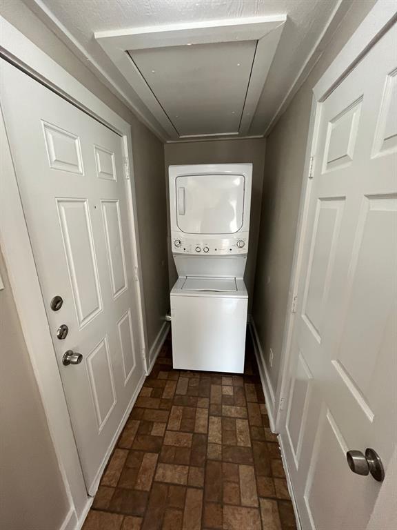 Laundry area featuring a stacked washer and dryer, tile flooring, and two white paneled doors