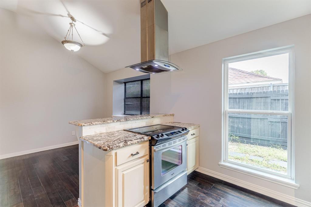 Kitchen featuring wood-finish flooring, stone-surfaced countertops, stainless steel range, and a stainless steel chimney-style vent hood