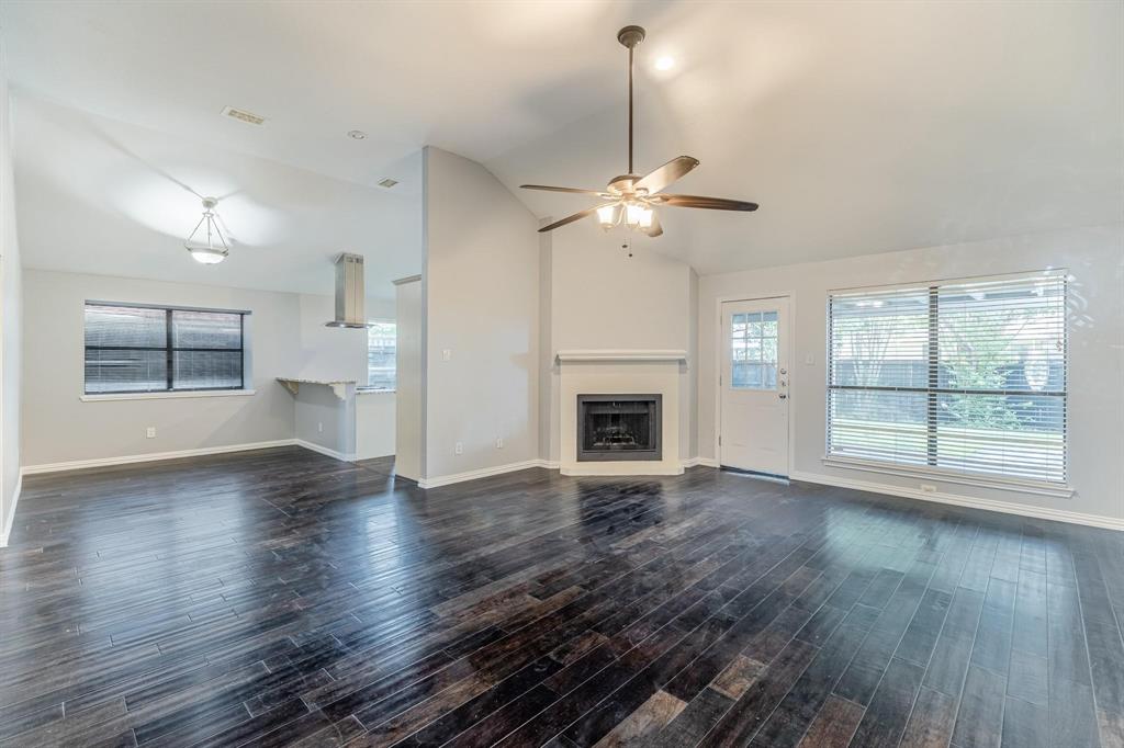 Vaulted ceilings with a central ceiling fan, dark wood-finish flooring, corner fireplace with a mantel, and recessed lighting