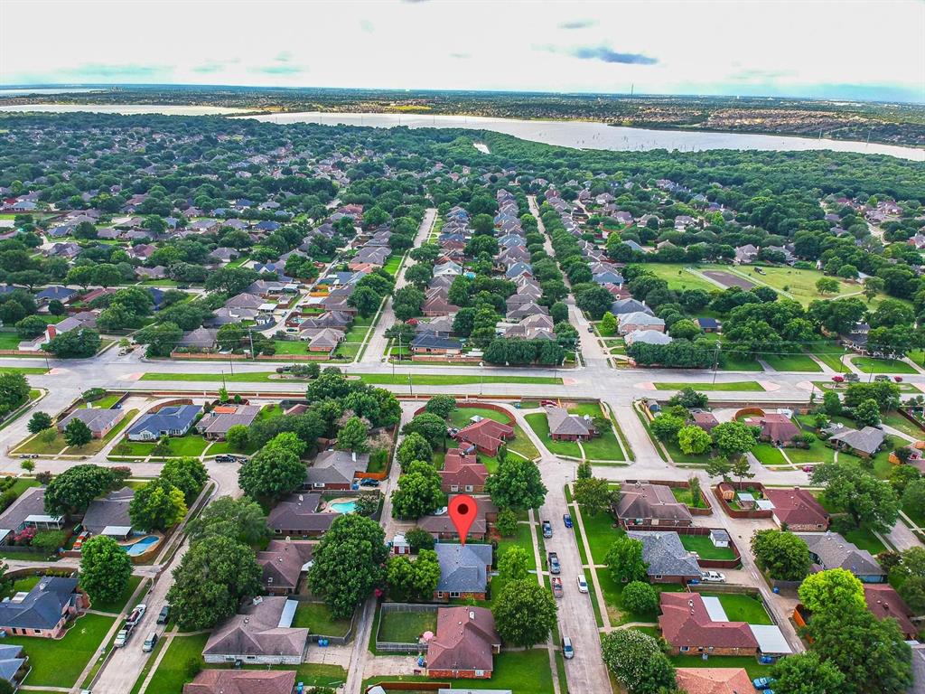 Aerial perspective featuring a residential lot with mature trees and proximity to a large body of water