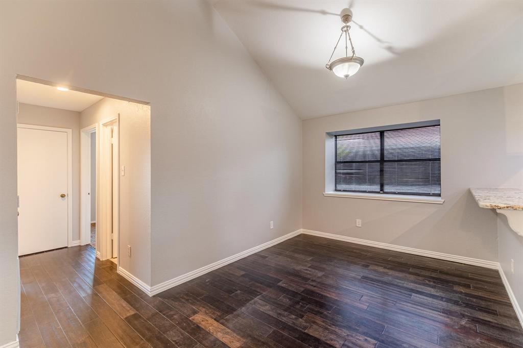 Vaulted ceilings, wood-finish flooring, neutral wall color, hanging light fixture, and stone-finish countertop edge