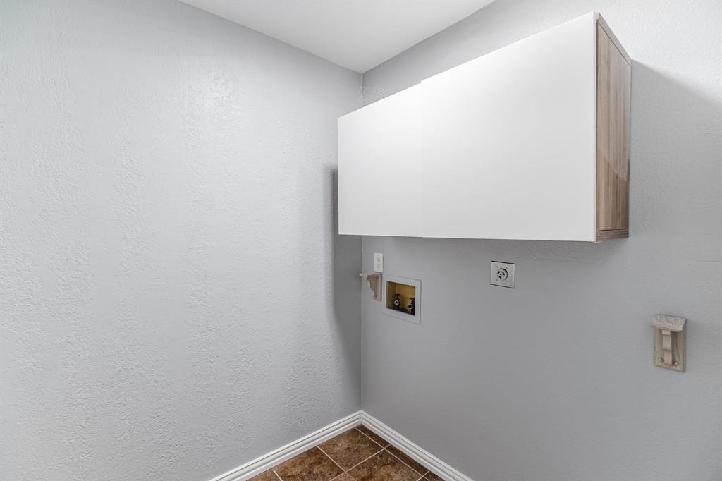 Wall-mounted cabinetry featuring a white finish with wood-tone side detailing and ceramic tile flooring