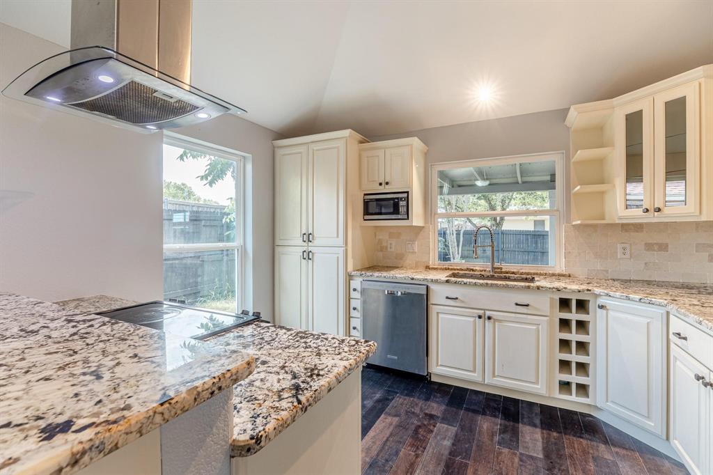 Kitchen featuring custom off-white cabinetry, stone-surface countertops, built-in wine storage, stainless steel appliances, and wood-finish flooring