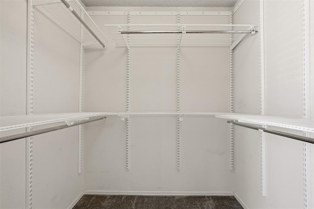 Walk-in storage space featuring adjustable white wire shelving and integrated metal garment rods