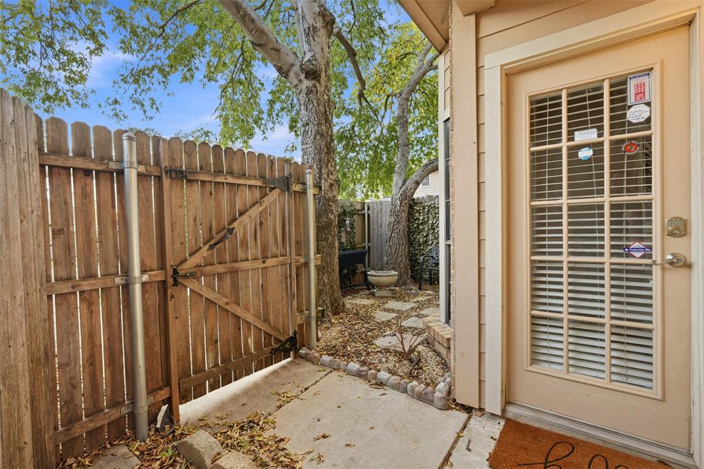 Exterior area featuring a wooden privacy fence, concrete patio, stepping stone pathway, and mature trees