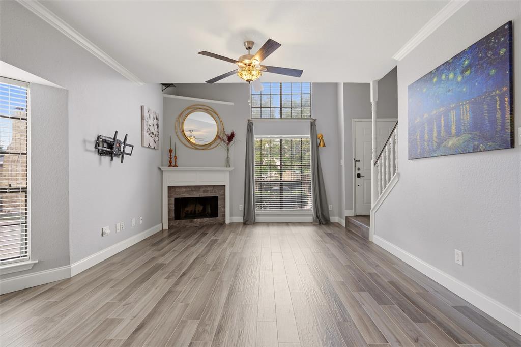 Wood-finish flooring, fireplace with a tiled hearth, vaulted ceiling, multi-pane windows, and a ceiling fan