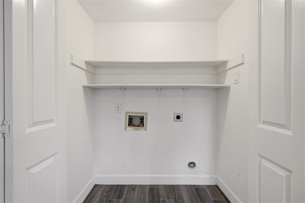 Laundry alcove featuring double-door entry, wood-finish flooring, and two tiers of built-in shelving