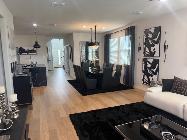 Open-concept living space featuring wood-finish flooring, recessed lighting, and a kitchen island with a stone-finish countertop Open-concept living space featuring wood-finish flooring, recessed lighting, and a kitchen island with a stone-finish countertop