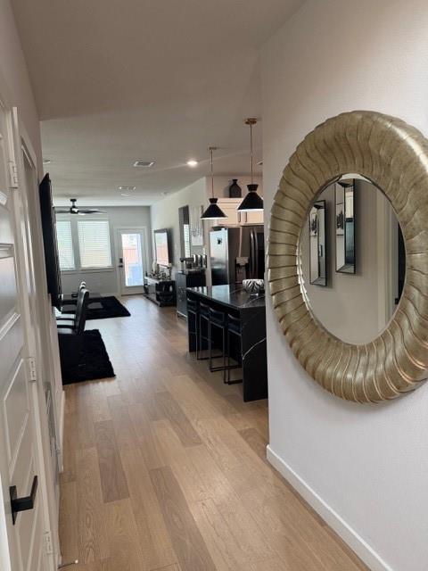 Wood-finish flooring, kitchen island with stone countertop, two industrial-style pendant lights, and recessed ceiling lighting Wood-finish flooring, kitchen island with stone countertop, two industrial-style pendant lights, and recessed ceiling lighting