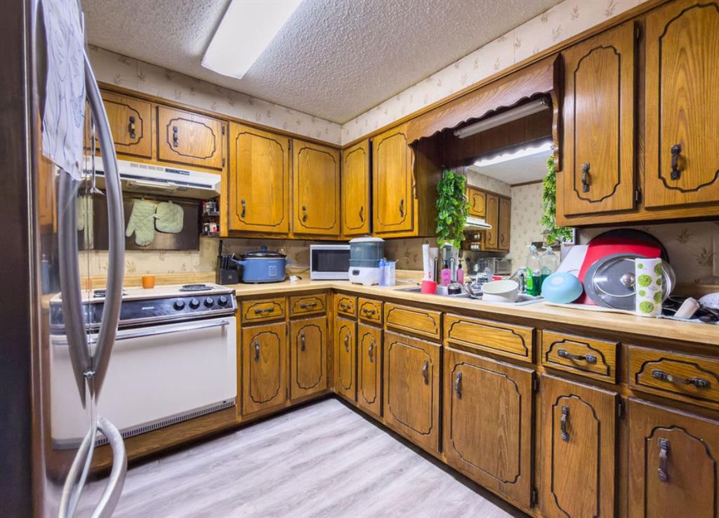 Kitchen featuring extensive wood cabinetry, wood-finish flooring, and a built-in range