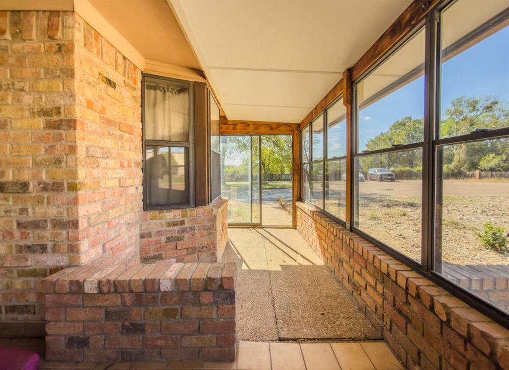 Enclosed sunroom featuring exposed brick walls, a built-in brick bench, expansive windows with dark frames, and sliding glass door access