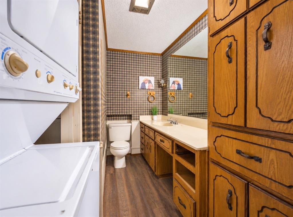 Bathroom featuring a wood-finish vanity with an integrated countertop, extensive built-in cabinetry, wood-finish flooring, and a full-width wall mirror