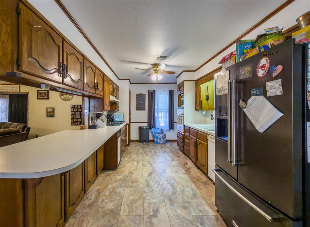Kitchen featuring solid-wood cabinetry, extended laminate countertops, integrated cooktop, built-in wall oven, and resilient vinyl tile flooring Kitchen featuring solid-wood cabinetry, extended laminate countertops, integrated cooktop, built-in wall oven, and resilient vinyl tile flooring