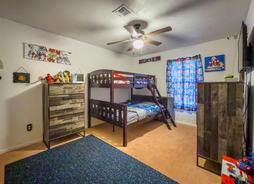 Room featuring wall-to-wall carpeting, a ceiling fan with integrated light fixture, and a window with blinds