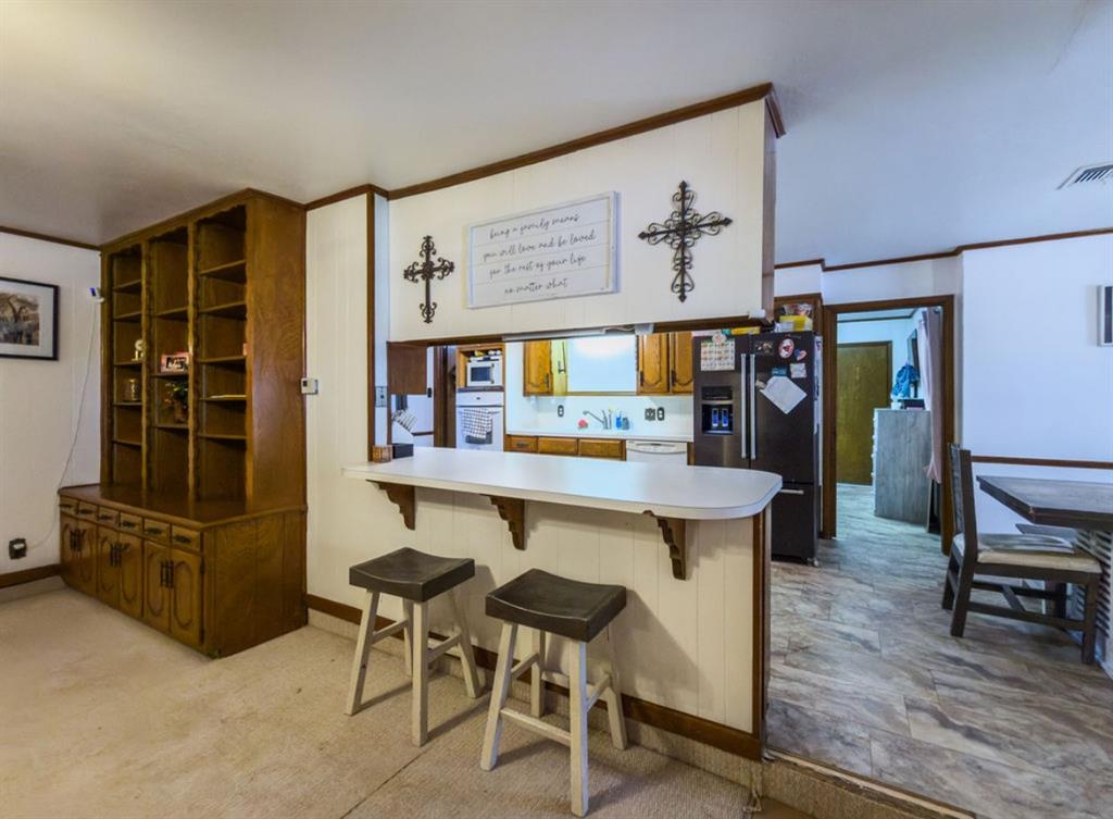Built-in floor-to-ceiling wooden shelving unit, pass-through kitchen window with a breakfast bar, and tile flooring Built-in floor-to-ceiling wooden shelving unit, pass-through kitchen window with a breakfast bar, and tile flooring