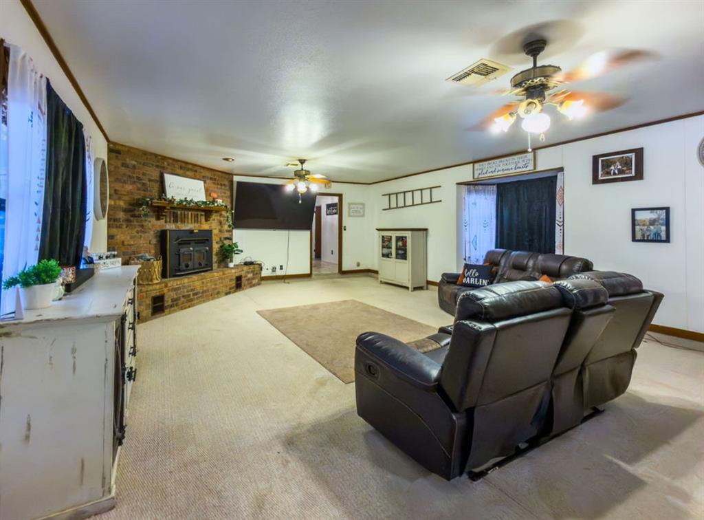Brick fireplace with a wood mantel, dual ceiling fans, and a bay window Brick fireplace with a wood mantel, dual ceiling fans, and a bay window