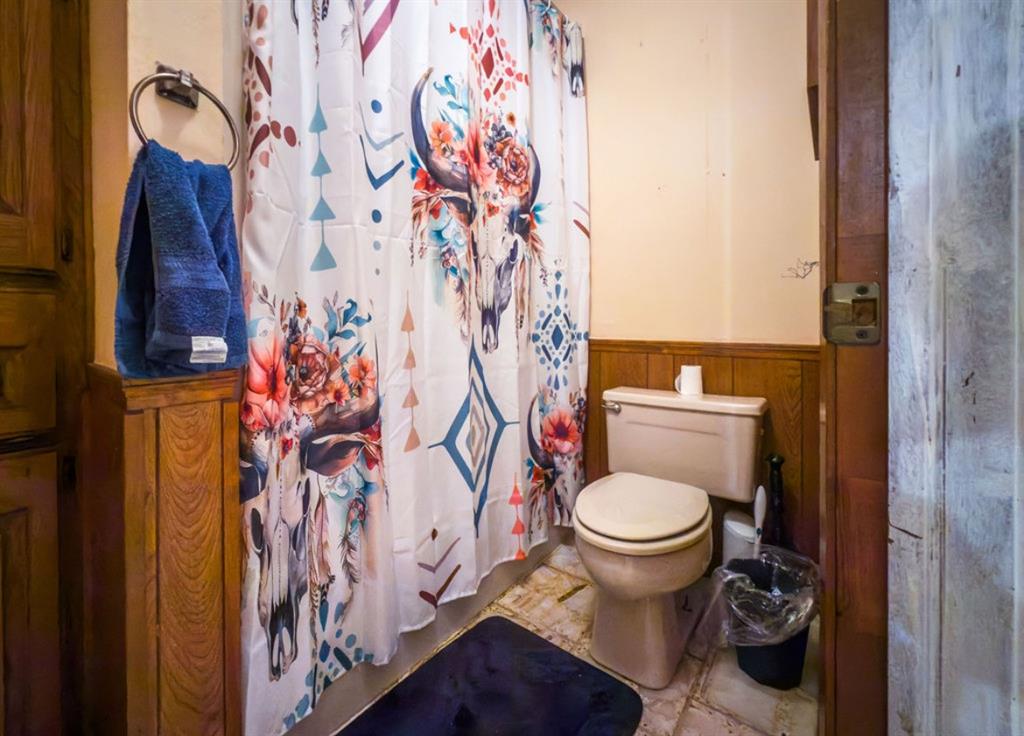 Bathroom featuring wood-finish paneling, a wall-mounted circular towel ring, and a standard-height porcelain toilet