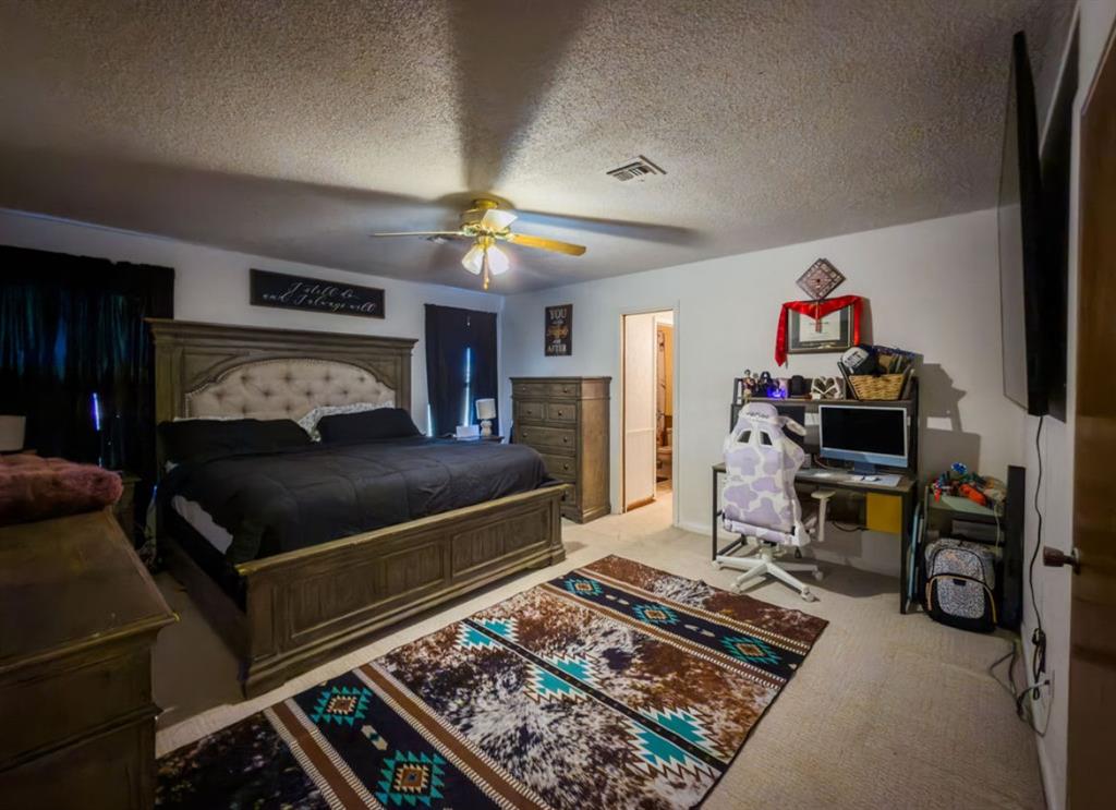 Spacious bedroom featuring neutral wall-to-wall carpeting and a central ceiling fan with integrated lighting Spacious bedroom featuring neutral wall-to-wall carpeting and a central ceiling fan with integrated lighting
