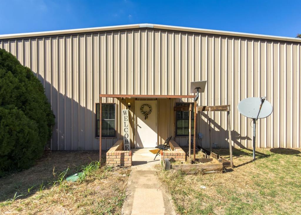 Metal-paneled exterior featuring a concrete walkway, brick-bordered entrance, and dual windows