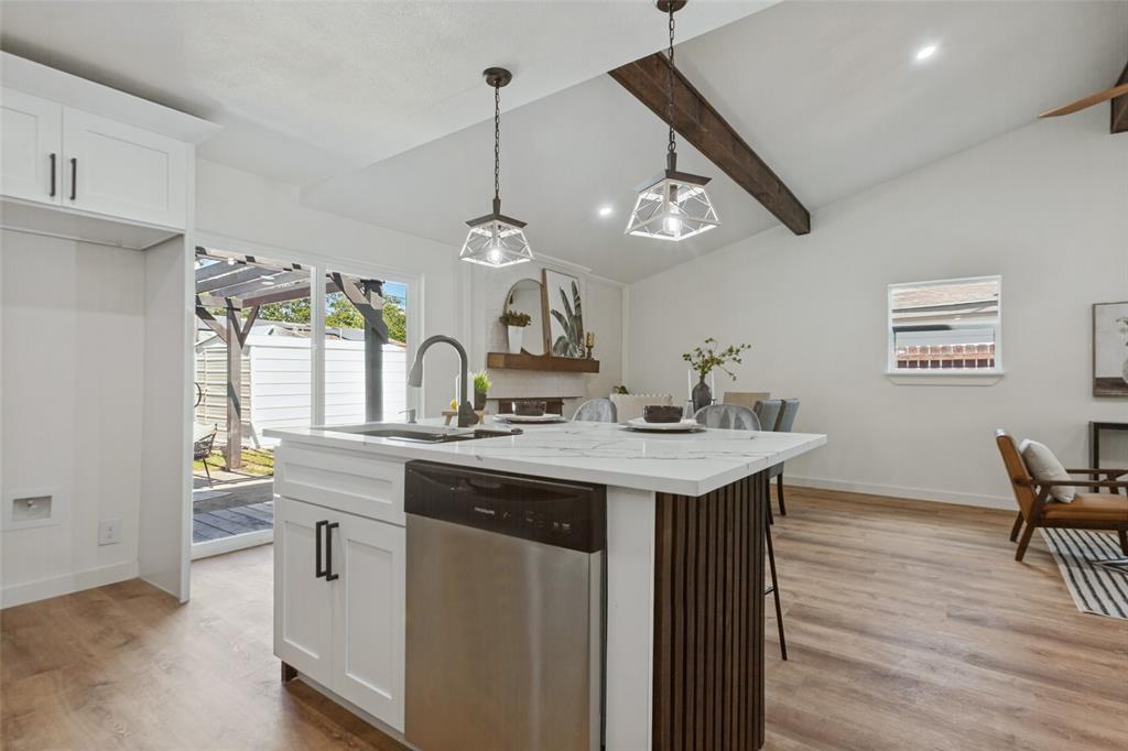 Kitchen island featuring a stone-look countertop, integrated stainless steel dishwasher, and vertical wood-slat detailing