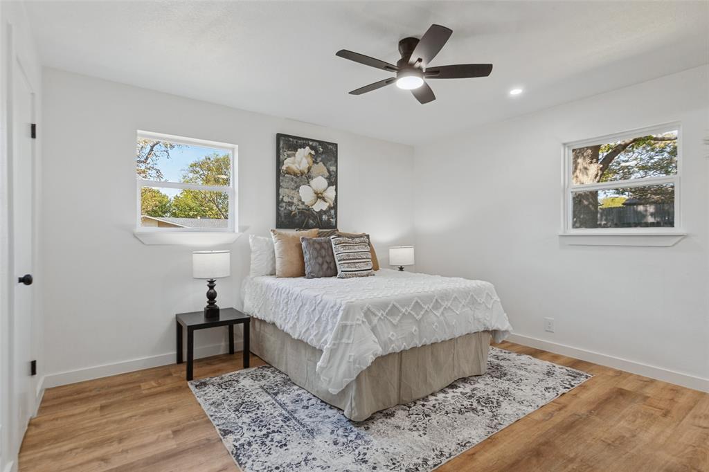 Bedroom featuring wood-finish flooring, dual windows with sills, and a centrally mounted ceiling fan with integrated lighting