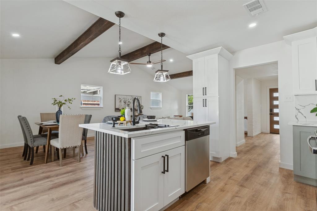 Kitchen island with a slatted base, white cabinetry, wood-finish flooring, exposed ceiling beams, and pendant lighting