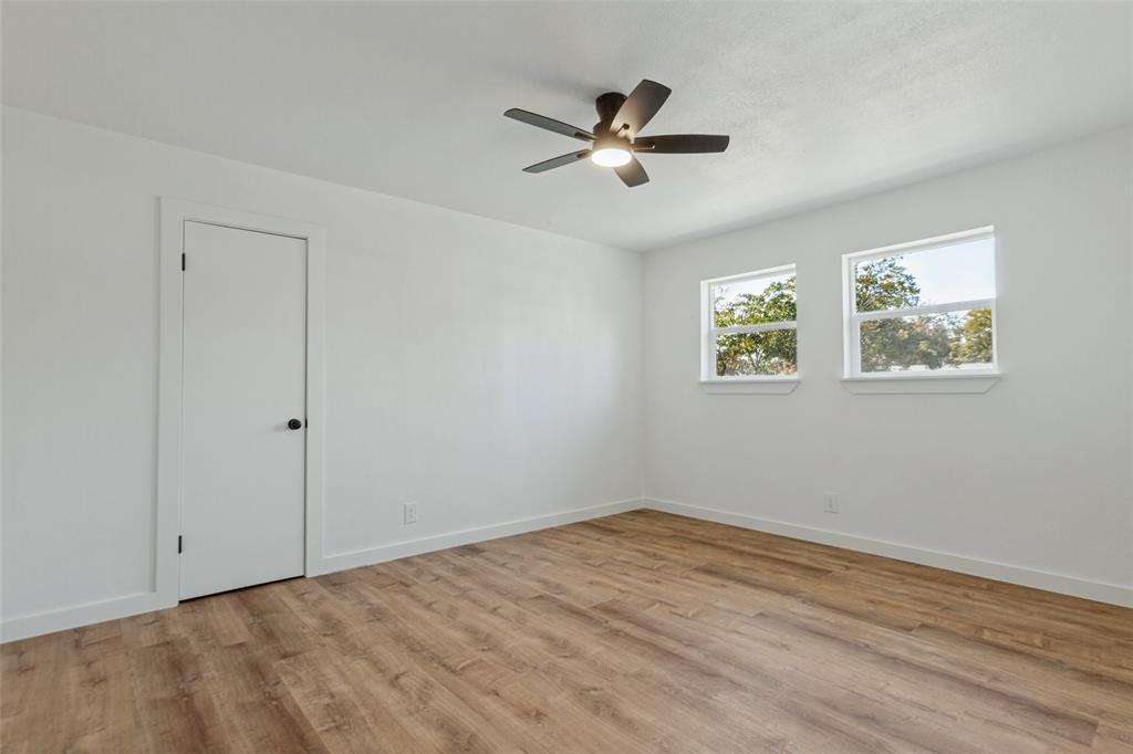 Room featuring wood-finish flooring, dual windows, and a ceiling fan with integrated lighting