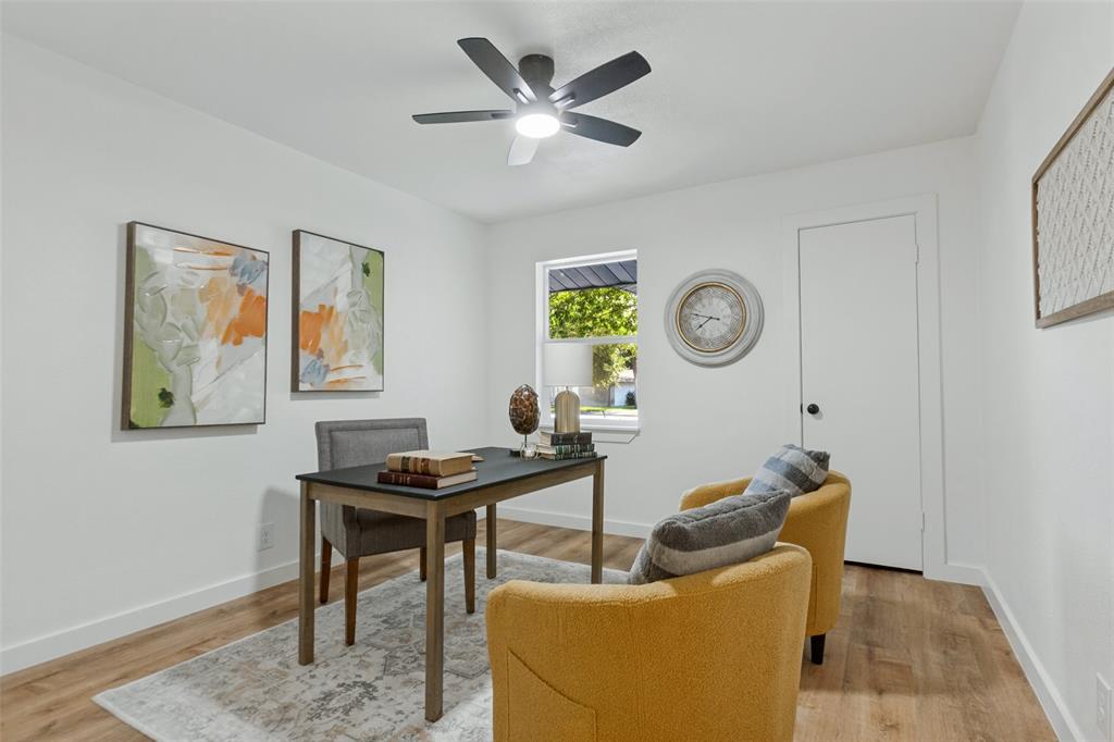 Interior room featuring wood-finish flooring, a neutral color palette, a single-hung window, and a multi-blade ceiling fan with integrated lighting