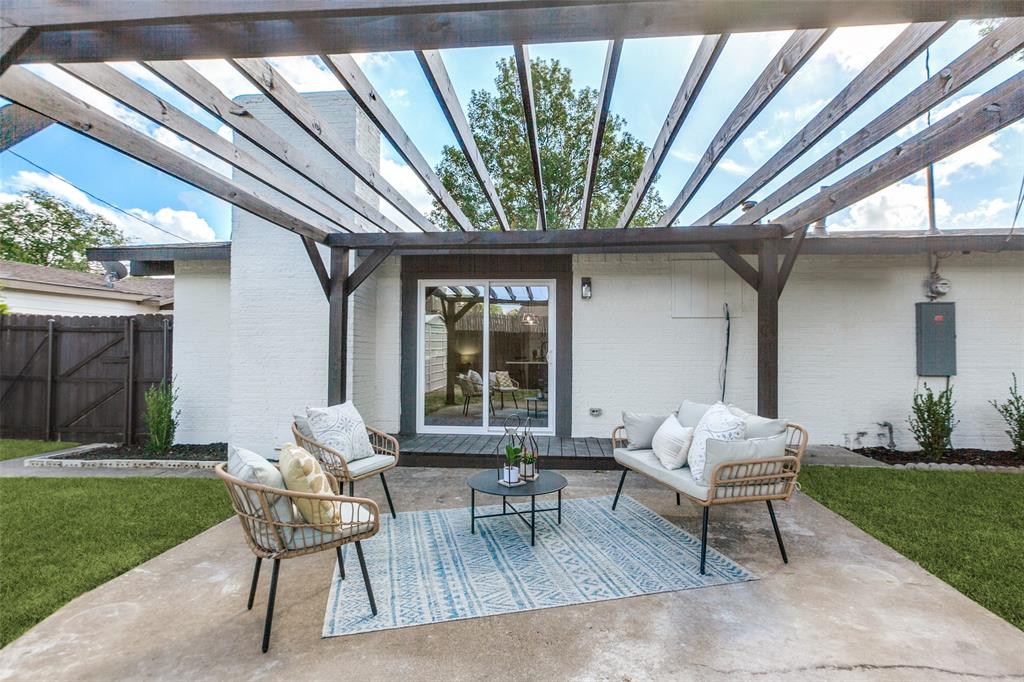 Rear patio featuring a wooden pergola, concrete flooring, sliding glass door, and white brick exterior